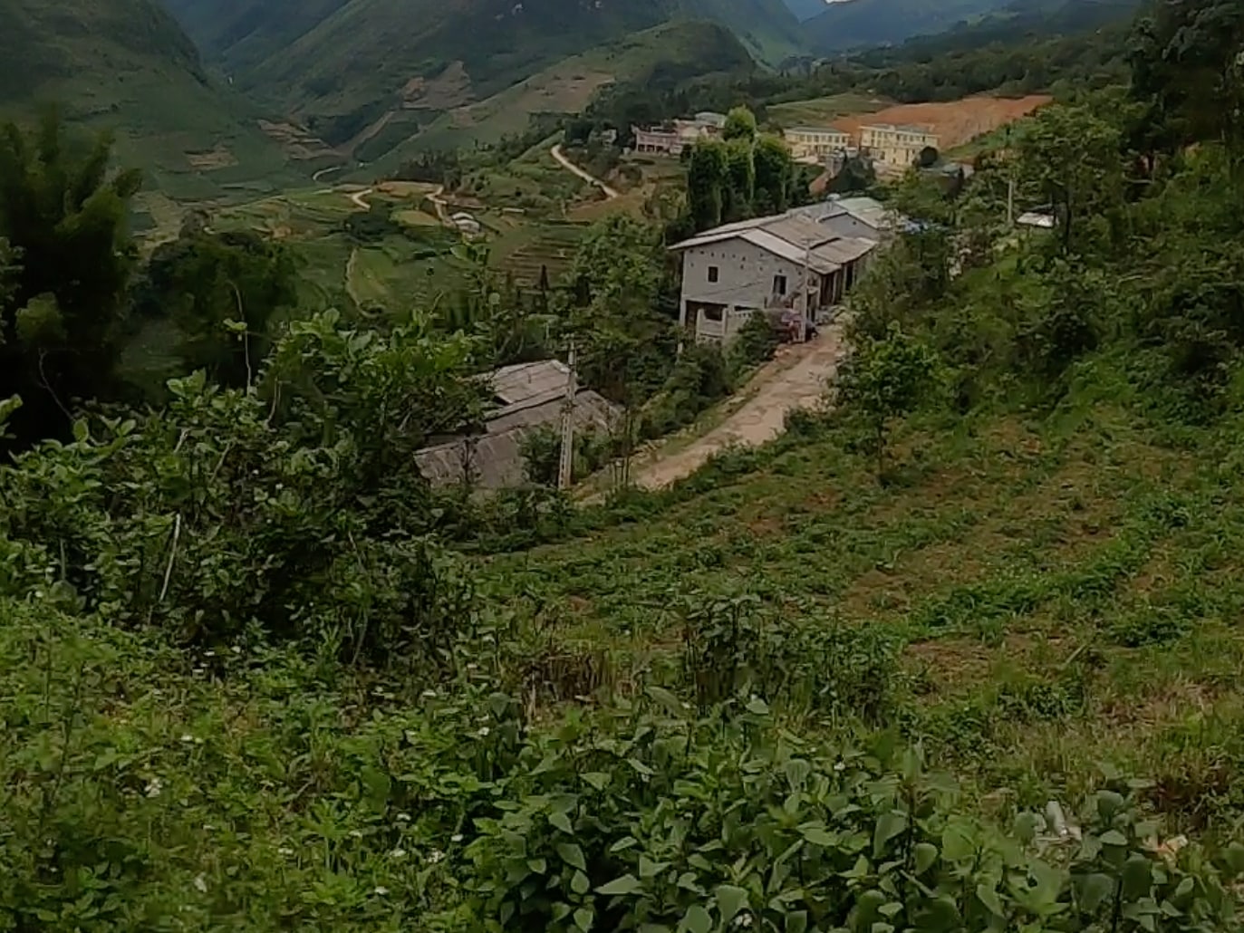 A village among green hills, with a road winding through the valley.