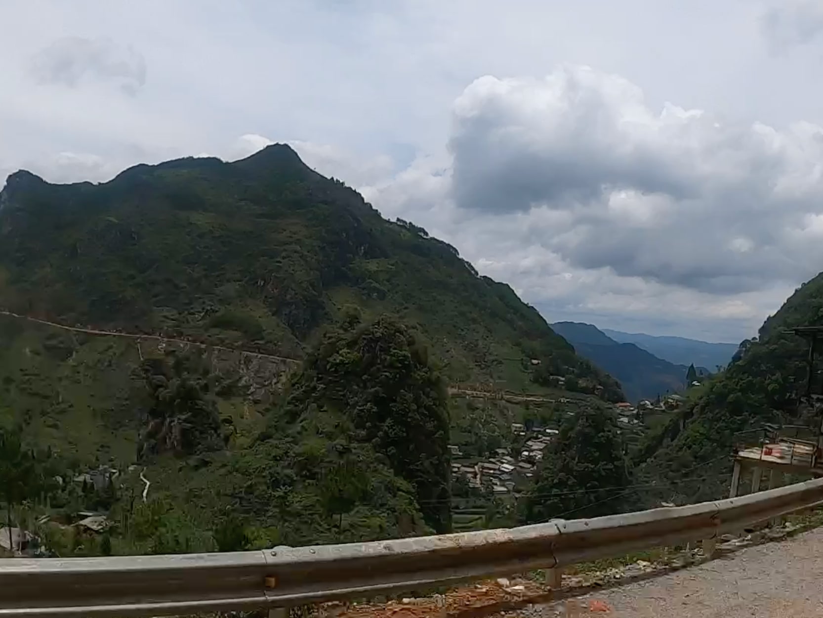 Terraced hills and a winding road viewed from the roadside.